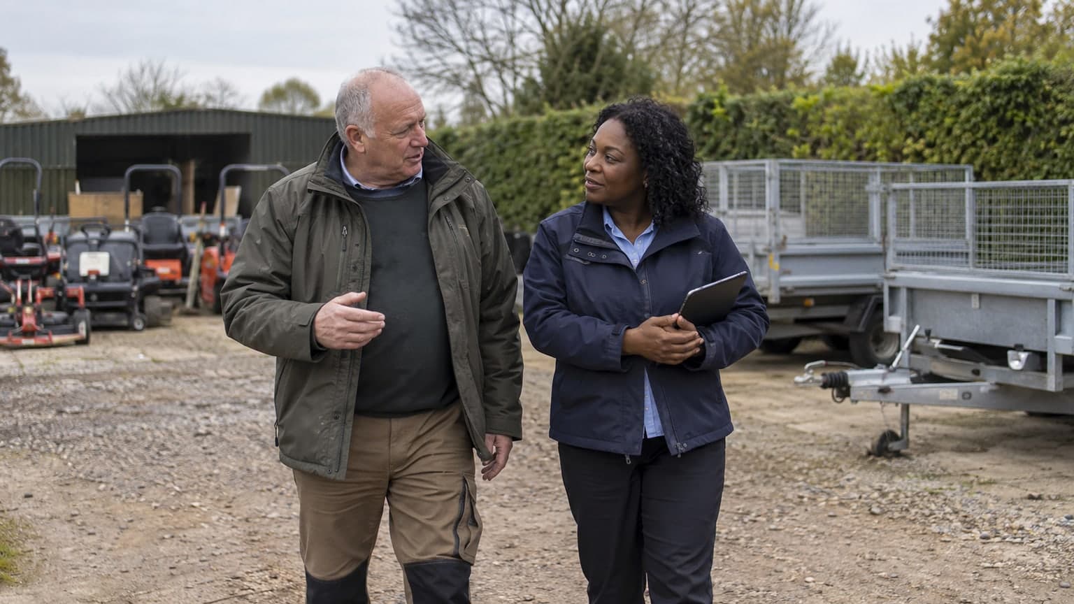 Two professionals walking through a landscaping equipment yard.