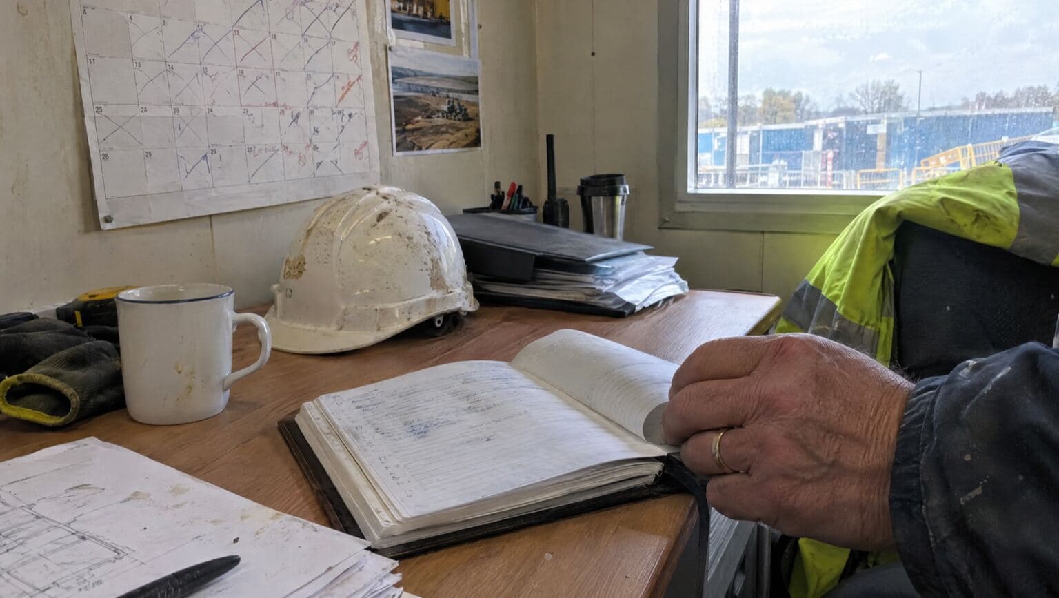 A wall calendar and diary on a contractor's office desk